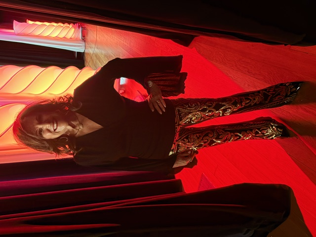 Iris Revson standing backstage in sequined pants under red stage lighting